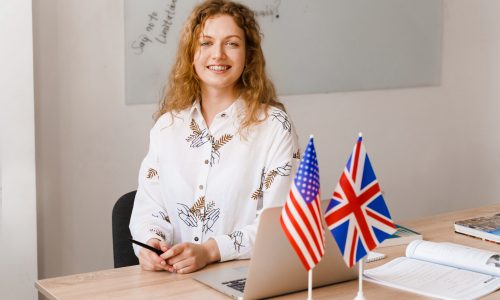 Close-up portrait of a beautiful smiling student on bright background. Happy ginger female teacher smiling to her colleagues
